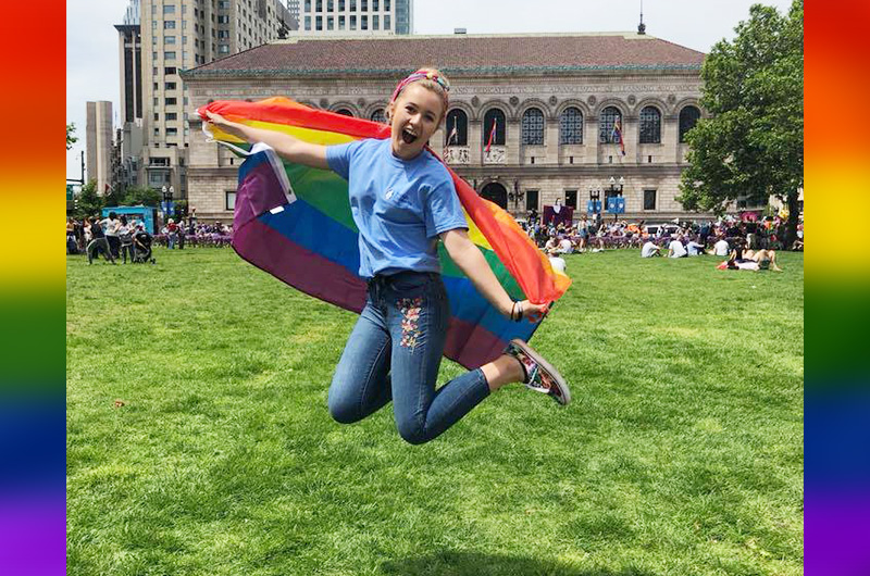 A girl jumps with a rainbow flag at the LGBTQ+ Pride Parade