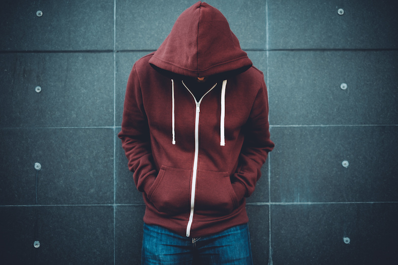 Depressed teen boy leans against wall