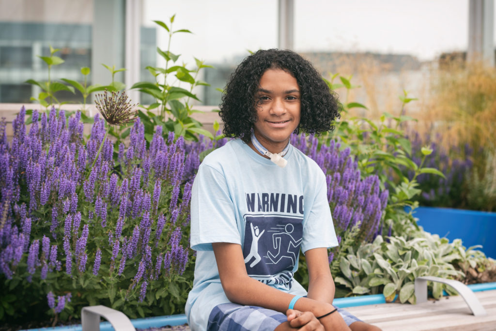 boy with esophageal damage sits in front of flowers