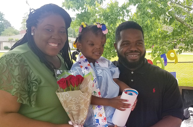 Zoey, who had surgery for a frontal encephalocele, with her mom and dad