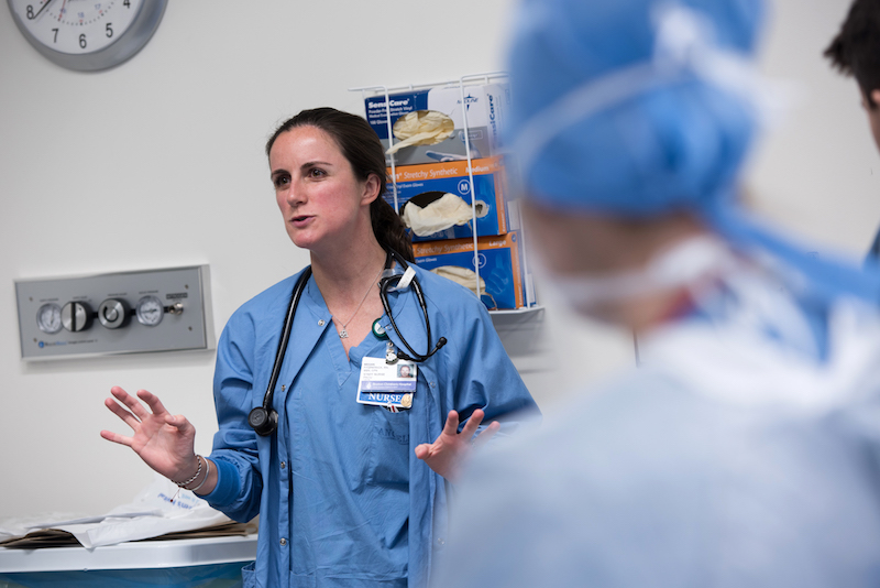 A nurse in the simulation lab talks to a group of patients scheduled for spinal fusion surgery.