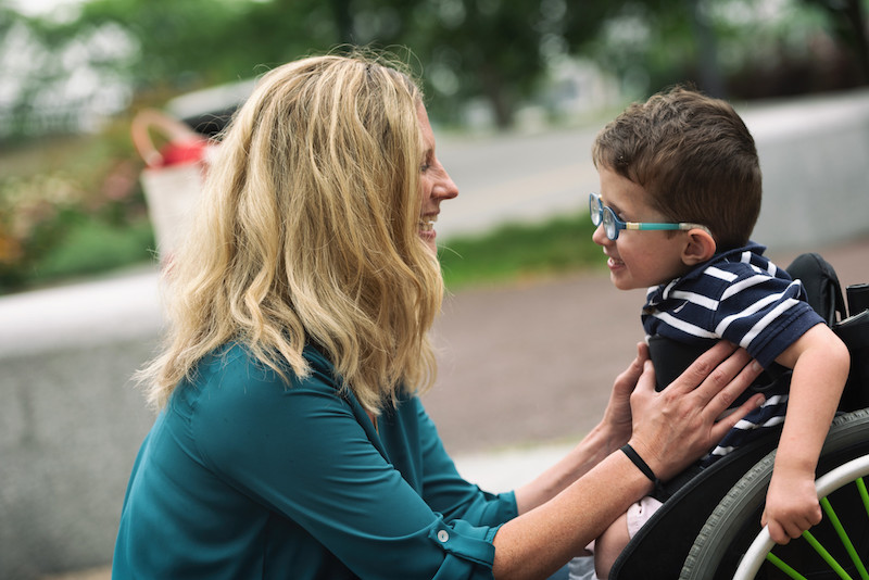 boy with spina bifida smiles at his mom