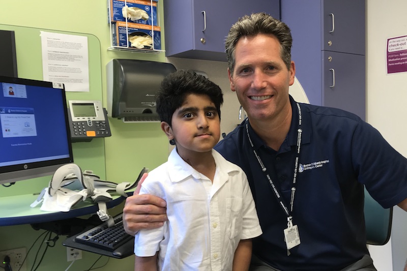 Saif and his physician pose together after the surgery that corrected his cervical spine.