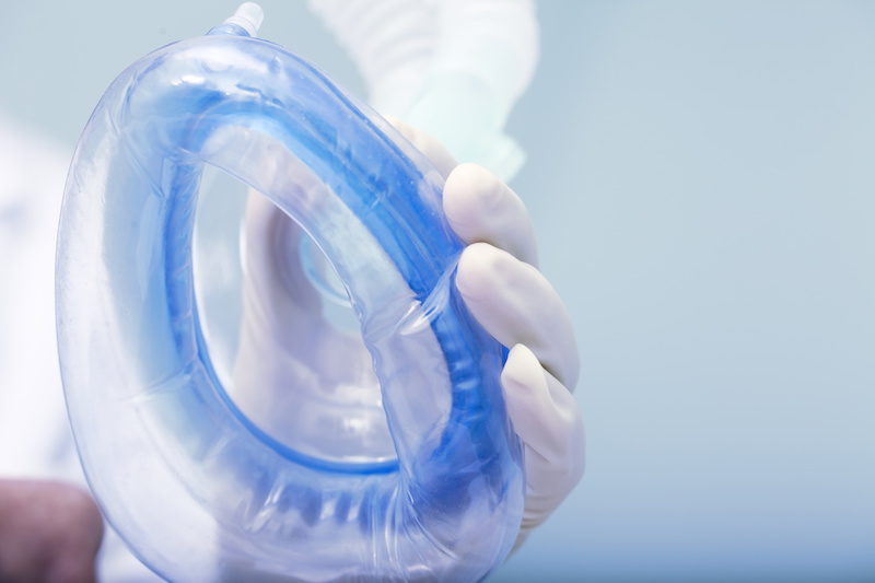 gloved hand holding anesthesia mask