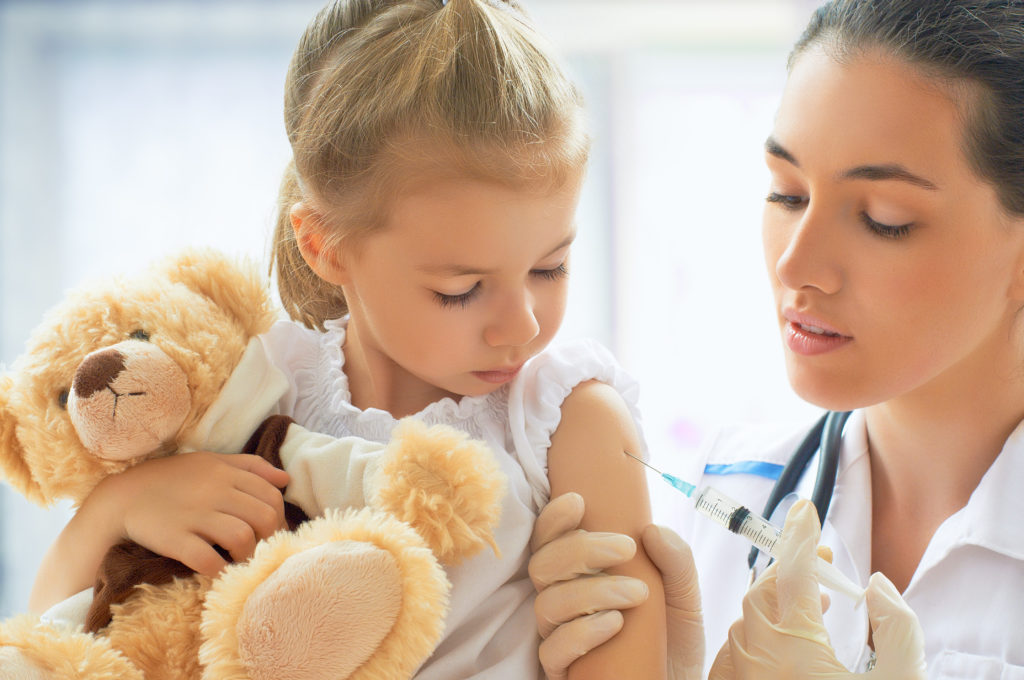 Doctor prepares to give little girl a flu shot.