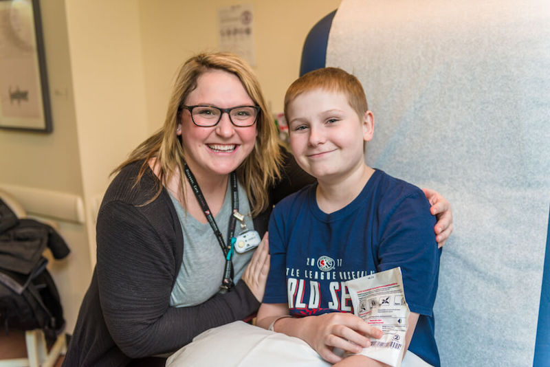 Cole, who had Car T-cell therapy, poses with his child life specialist.