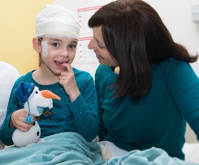 Mila in the hospital with her mom before receiving her custom treatment for Batten disease