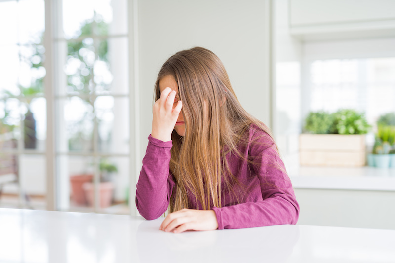 girl with chronic headache holds her head in pain