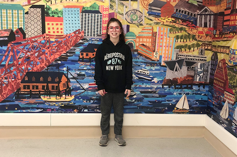 ghirl with cdh stands in front of a mural