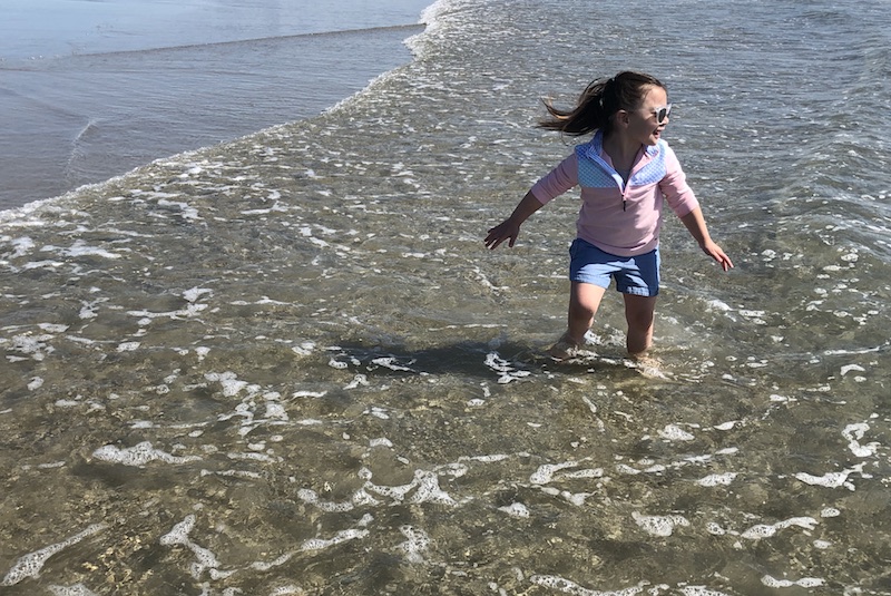 Grace, who had surgery for a cavernous malformation, runs in the water at the beach.