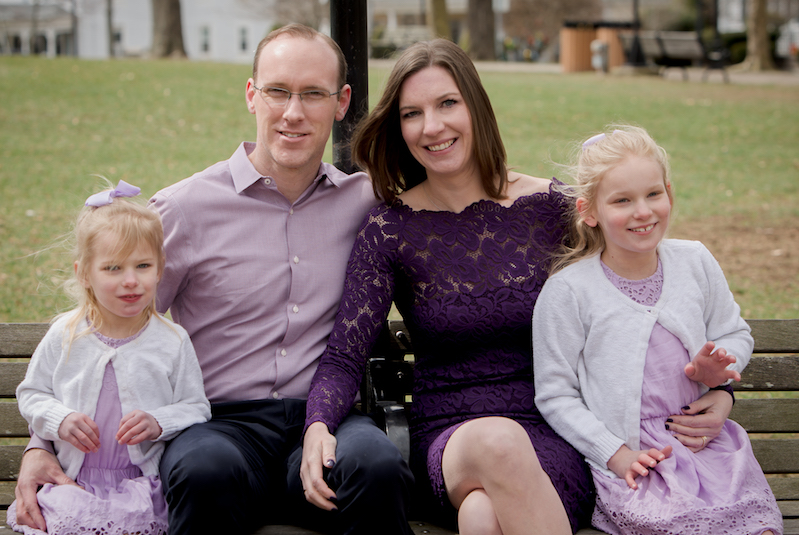 Sisters Elise and Lily, who have SYNGAP1, pose on a bench with their parents.