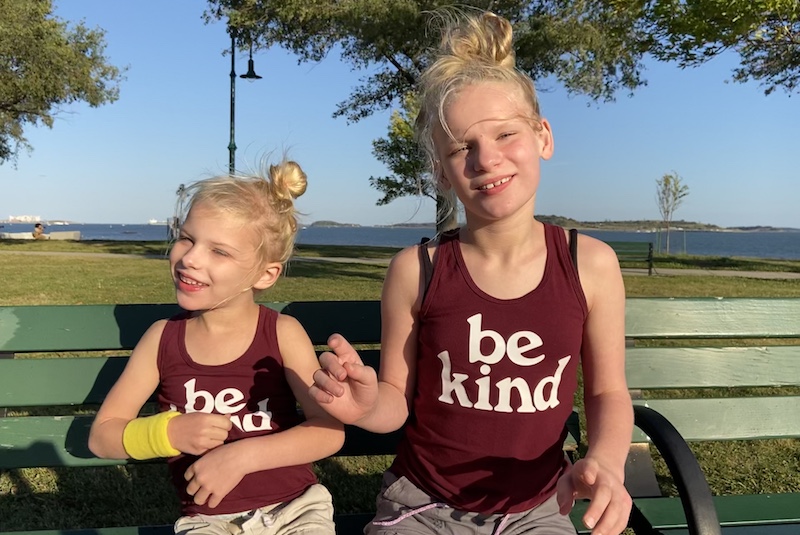 Sisters Elise and Lily, who both have SYNGAP1, sit on a bench outside