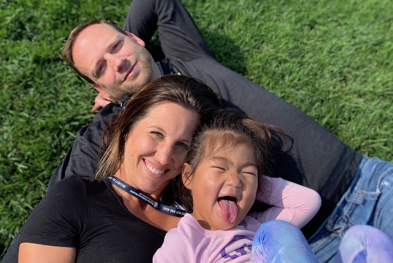 Faith, who had single ventricle surgery, poses in the grass with her parents