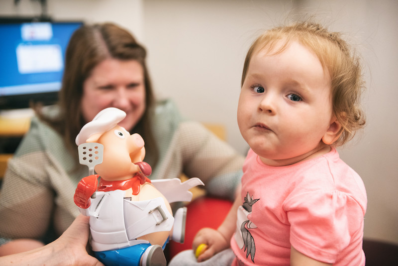 Sofie, who has SMA, plays with a pig during a session with her physical therapist