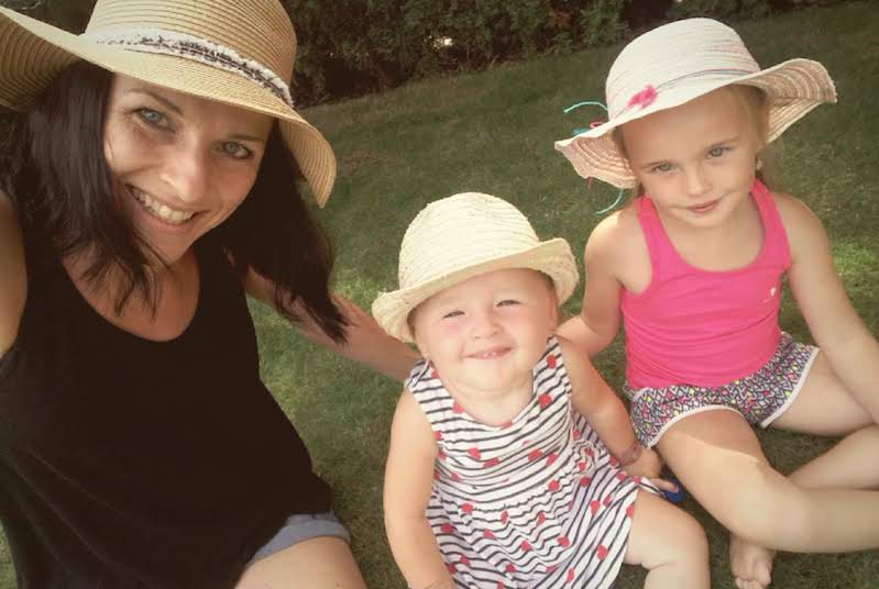 Sofie, who has SMA, sits outside with her mom and sister