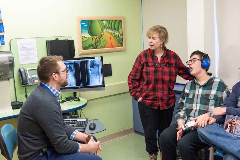 Dr. Birch, orthopedic surgeon, consults with family of patient who had spinal fusion surgery.