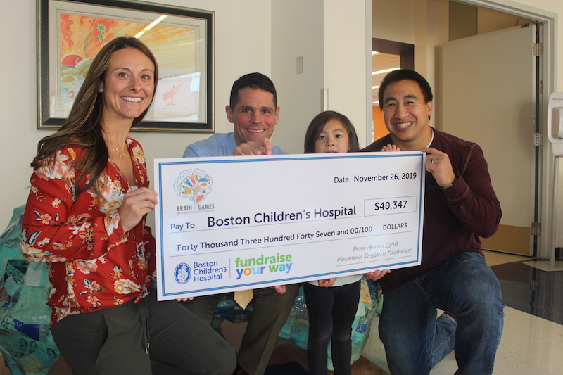 A girl who had moyamoya surgery and her family present a check to the doctor who performed her surgery