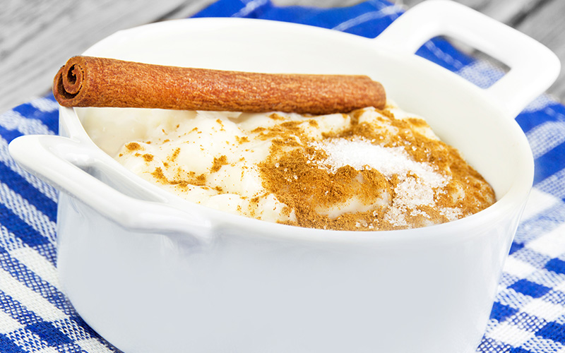A photo of a bowl of rice pudding, safe with kids with food allergies, is topped with cinnamon