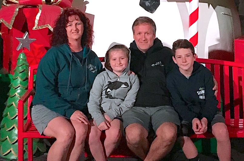 Caden, who had a limb difference caused by a lawnmower accident, sits on a bench with his family.