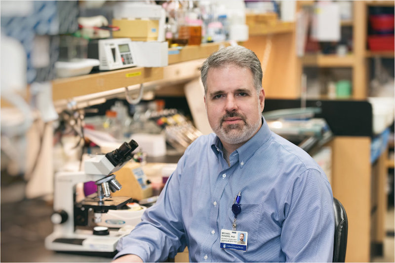 photo of Michael Rogers sitting at lab bench facing camera