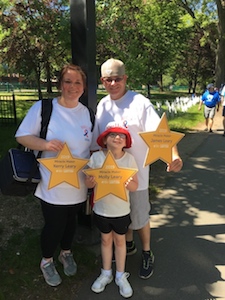 The Leary family holds gold stars with their names on them in a park on a summer day.
