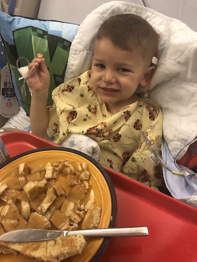 Evan, who had surgery for a brain tumor, eats pancakes in his hospital bed after surgery