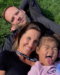 Nicole, Charlie, and Faith lay on the grass with Faith making a funny face.