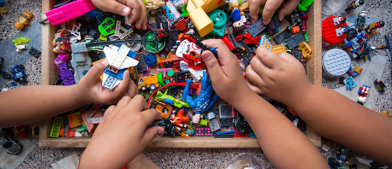 Hands of many children who are playing toys together.