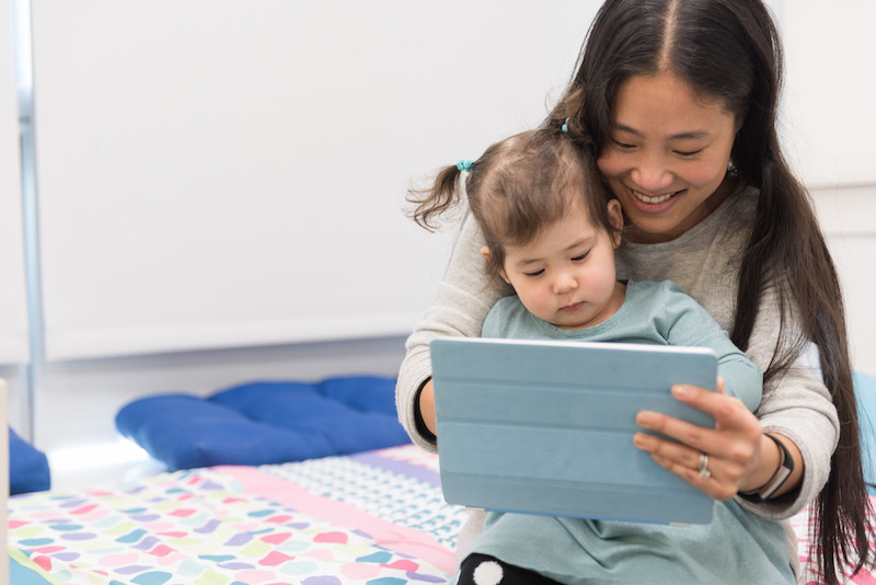 Mom and toddler look into a computer for a virtual visit