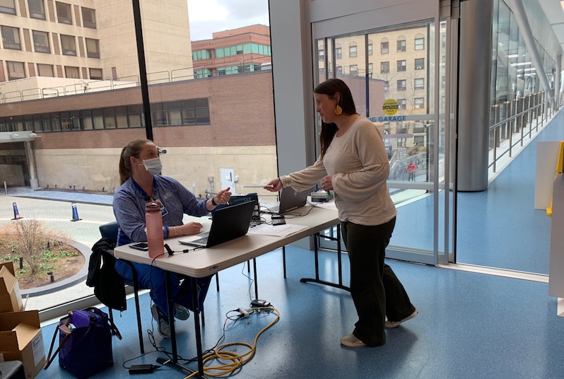 Image of a nurse wearing a face mask checking a parent's credentials at Boston Children's during the COVID-19 outbreak