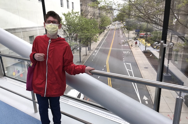 Jared in a red jacket on the Boston Children's skybridge overlooking an empty street.