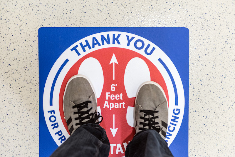 Sticker on the floor reminding people to maintain at least 6 feet of physical distance to prevent the spread of coronavirus.
