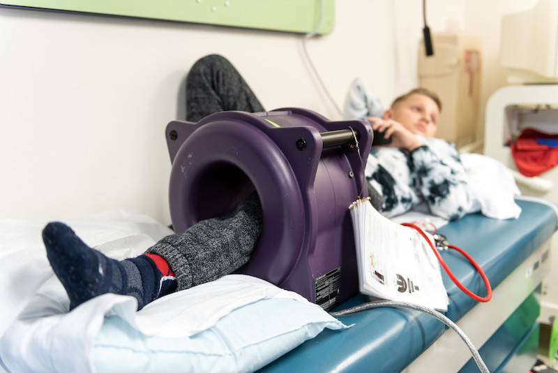 Nolan, who had limb-salvage surgery as part of his treatment for bone cancer, has his leg lengthened. His leg rests inside a large circular device that contains a high-strength magnet.