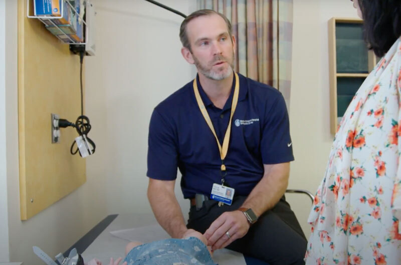 Dr. May examines an infant with clubfoot while talking with the chid's mother.