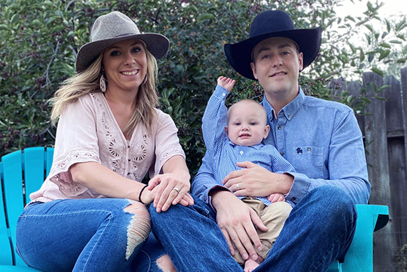 Matt, who has hemophilia A, sits with his wife, Ashley, and son, Daxton. They are wearing cowboy hats and sitting on blue chairs