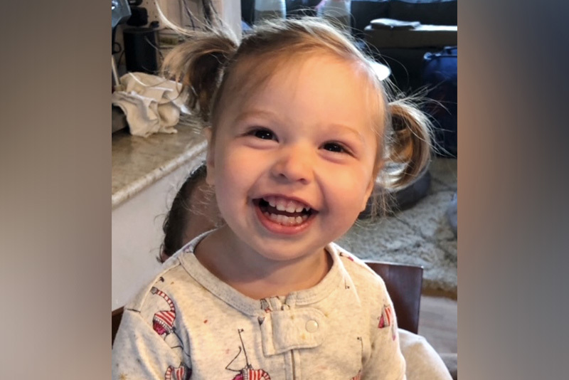 hadley, who had a stroke, smiles at the camera. her hair is in ponytails