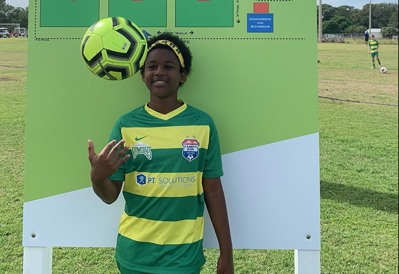 Asada, who has aplastic anemia, holds a soccer ball on a field.